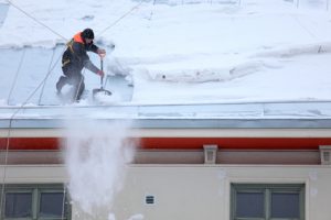 Man is de-icing a snowy Roof