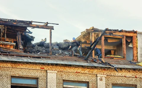 stock-photo-unrecognizable-construction-team-dismantle-charred-roof-in-the-aftermath-of-fire-post-fire
